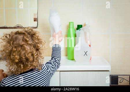 Petit enfant tend la main aux produits chimiques ménagers. Garder hors de portée des enfants. Dangers à la maison pour les enfants concept. Banque D'Images