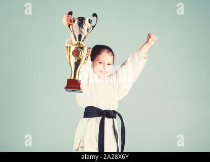 Petite fille avec champion cup. arts martiaux. gagnant petite fille dans gi sportswear. pratiquer le Kung Fu.. de la petite enfance et de l'activité de l'énergie. pour les enfants. sport succès en combat singulier. Beauté sportive. Banque D'Images