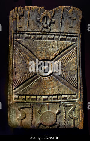 Une porte de grenier en bois sculpté du début du XXe siècle avec des motifs géométriques en relief, des motifs d'animaux stylisés et un masque de figure ancestral central, conçu par le peuple Sénoufo de Côte d'Ivoire, photographié sur un fond noir solide. Banque D'Images