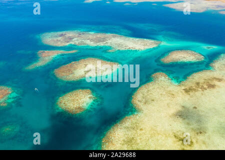 Les récifs coralliens et lagons, vue d'en haut. Atolls et la mer turquoise de l'eau. La surface de la mer. Banque D'Images