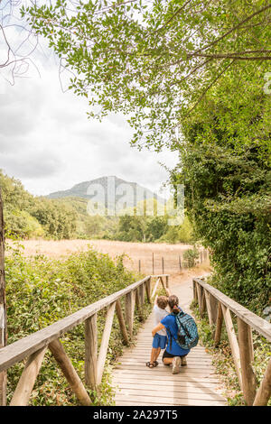 Une femme et un enfant de la randonnée, marche à pied le long d'une passerelle en bois qui traverse une forêt. Concepts de la vie de famille et vie saine. Banque D'Images