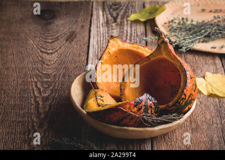 Les citrouilles au four au thym les herbes dans le bol en céramique de table rustique à base de plantes,la nourriture, l'automne Nature morte avec légumes de saison et des feuilles jaunes Banque D'Images