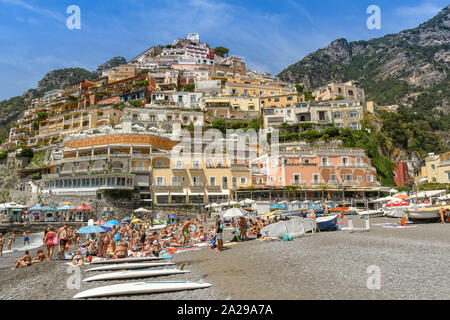 POSITANO, ITALIE - AOÛT 2019 : Planches de surf et les gens sur la plage de Positano. Dans l'arrière-plan sont les bâtiments colorés de la ville. Banque D'Images