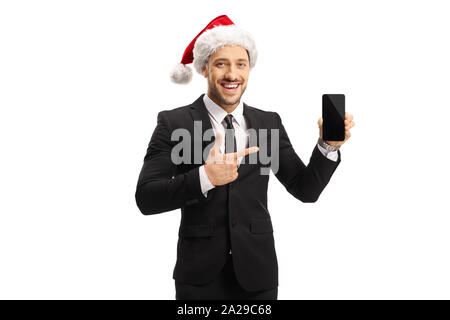 Jeune homme en costume portant un chapeau de Noël, la tenue d'un téléphone mobile et de pointage isolé sur fond blanc Banque D'Images