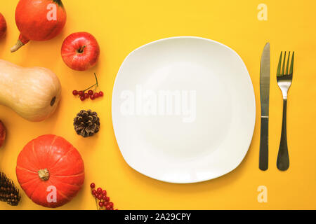 Plaque blanche vide pour le texte, les fruits rouges, les citrouilles et les pommes contre l'arrière-plan jaune. L'automne ou à l'automne fête de concept. Banque D'Images