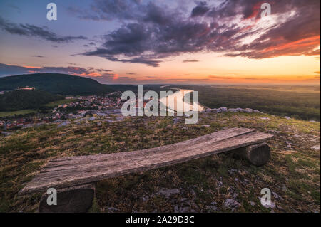 Point de vue des petites Ville de Hainburg an der Donau avec Danube vus de Braunsberg Hill au beau coucher du soleil. Banc en bois en premier plan. Banque D'Images