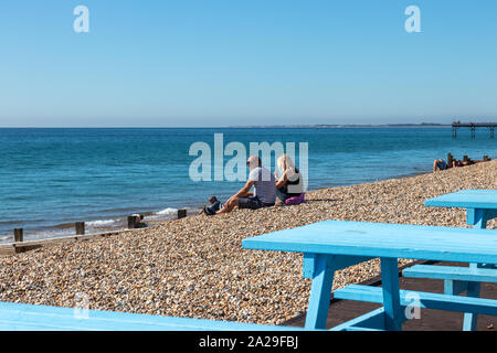 Un couple d'âge moyen s'est assis sur une plage de galets, le soleil brille sur un jour d'été Banque D'Images