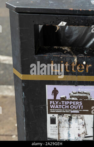 Un anti-fly tipping poster collé à une corbeille publique sur une rue de ville de Londres Banque D'Images