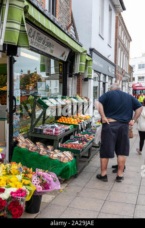 Les personnes à la recherche de fruits et légumes sur le stand d'une tradition de légumes dans un village anglais Banque D'Images