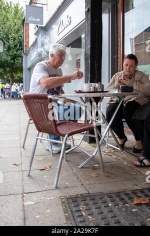 Un couple prendre un café assis à une table à l'extérieur d'un cafe Banque D'Images