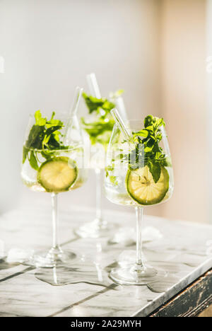 Hugo vin pétillant cocktail à la menthe fraîche et de la chaux dans les verres avec l'éco-friendly de pailles sur comptoir de cuisine en marbre blanc, selective focus. L'image froide Banque D'Images