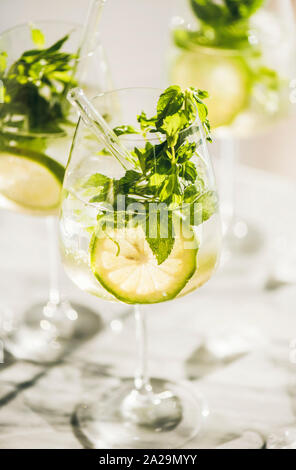 Hugo vin pétillant cocktail avec feuilles de menthe fraîche et lime slices dans les verres avec l'éco-friendly de pailles sur comptoir de cuisine en marbre blanc, sélective f Banque D'Images