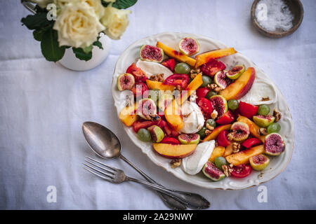 Peach, figues, raisins, tomates cerises, mozzarella et noix salade dans un plat de service Banque D'Images