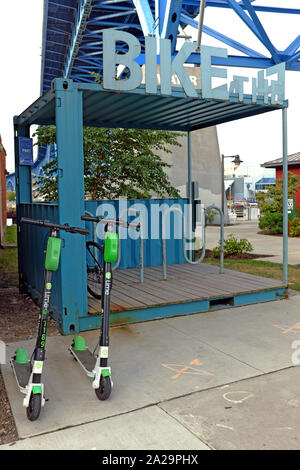 Un rack de vélos est vide sur la East Bank of the Flats de Cleveland, Ohio, tandis que deux scooters de chaux sont stationnés devant. Banque D'Images