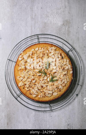 Amande sans gluten le romarin gâteau maison décorée par almond sur grille de refroidissement sur fond texture gris. Mise à plat, de l'espace Banque D'Images