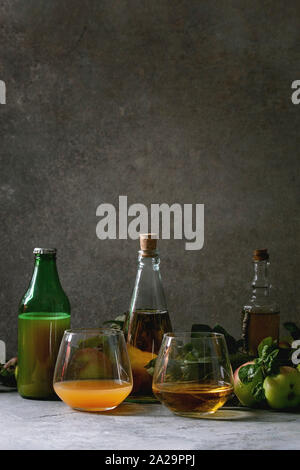 Variété de boissons d'Apple. Bouteilles verres d'ang le jus de pomme, le vinaigre de cidre de pommes et le jardin avec des feuilles et branches sur table avec dark backgrou Banque D'Images