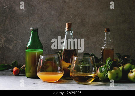 Variété de boissons d'Apple. Bouteilles verres d'ang le jus de pomme, le vinaigre de cidre de pommes et le jardin avec des feuilles et branches sur table avec dark backgrou Banque D'Images