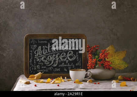 Tasse de café expresso et vintage tableau lettrage manuscrit sur le linge de table cloth avec l'automne jaune feuilles et baies en vase en céramique. The w Banque D'Images