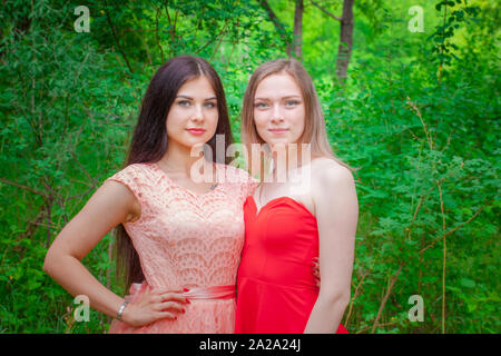 Portrait commune de deux amis. Belles jeunes filles posant dans de belles robes. Les femmes dans le contexte de la forêt. Banque D'Images