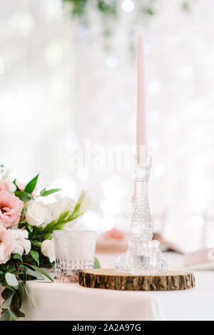 Une grande bougie paraffine fine de couleur rose doux dans un chandelier en verre. Banque D'Images