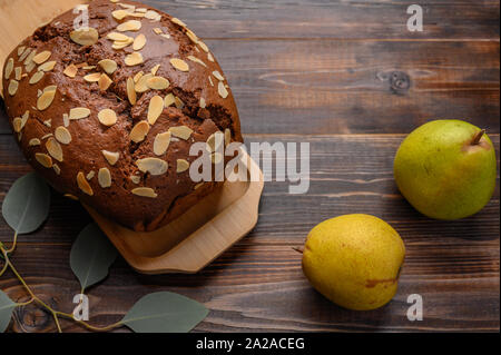 Poires au chocolat maison cake au gingembre et cardamome sur un plateau en bois à côté de la poire et une branche avec des feuilles Banque D'Images