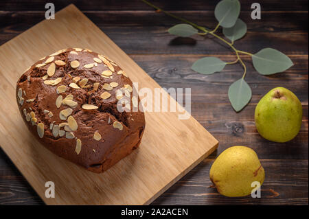 Poires au chocolat maison cake au gingembre et cardamome sur une planche de bois. À côté de la poire et des branches avec des feuilles Banque D'Images