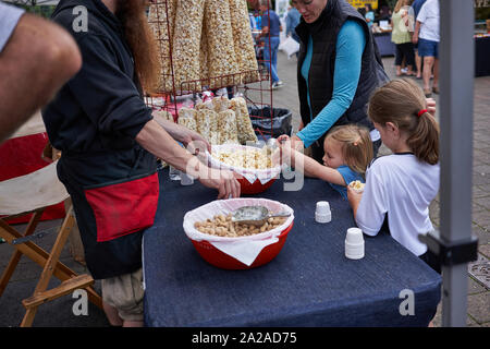 Un vendeur offre des échantillons de maïs soufflé gratuits à une petite fille au marché agricole du samedi à Lake Oswego, Oregon, le 14 septembre 2019. Banque D'Images