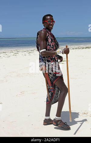 Homme massaï avec canne debout sur la plage, Zanzibar, l'île de Unguja, Tanzanie. Banque D'Images