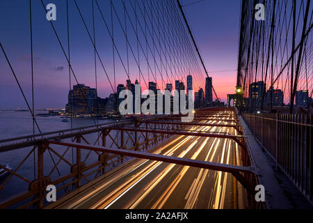 Pont de Brooklyn avec sentiers de lumière et vue sur Lower Manhattan, juste après le coucher du soleil. Soir à New York, NY, USA