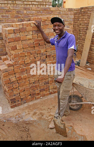 Construction Worker standing next to pile de briques, Moreleta Park, Pretoria, la Province de Gauteng, Afrique du Sud. Banque D'Images