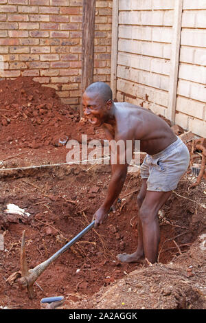 Travailleur de la Construction avec pioche creuser un trou pour une petite piscine, Moreleta Park, Pretoria, Gauteng, Afrique du Sud. Banque D'Images