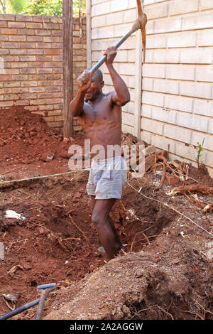 Travailleur de la Construction avec pioche creuser un trou pour une petite piscine, Moreleta Park, Pretoria, Gauteng, Afrique du Sud. Banque D'Images