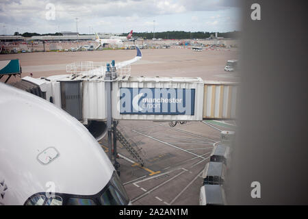 Un avion stationné à la porte de l'aéroport de Manchester, au Royaume-Uni. L'accent est mis sur la passerelle adjacente à l'avion pour permettre aux passagers de s'embarquer et de descendre. Banque D'Images