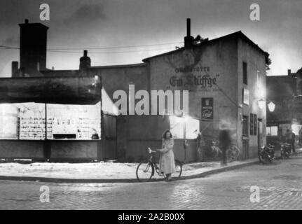 Une scène de rue dans l'après-guerre, l'Allemagne (Cologne) par nuit. Dans le centre est une femme avec vélo (photo non datée). Banque D'Images