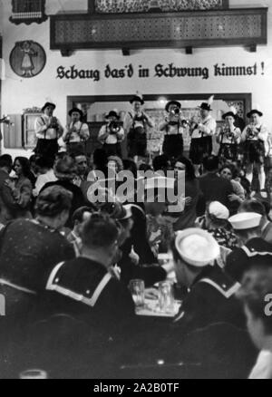 Les marins et les autres invités et de boire une bière et écouter de la musique en laiton dans une taverne bavaroise à St Pauli / Hambourg. Sur le mur est écrit en dialecte bavarois chaug "das'd dans kimmst Schwung !' (je vous vois venir à la vie). Banque D'Images