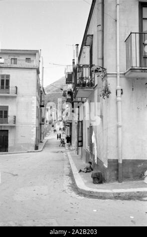 Vue d'une ruelle et plusieurs maisons dans la petite ville de Montelepre dans la province de Palerme (Sicile). Des enfants jouent dans la rue. Montelepre dans la province de Palerme (Sicile) est à 26 km seulement de la ville de Palerme. Ancien héros folklorique sicilien Salvatore Giuliano est né à Montelepre en 1922, et il est enterré dans le cimetière (Ostfriedhof) de la ville. Les habitants de Montelepre vivent principalement de l'agriculture. Banque D'Images