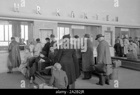 Photo de passagers qui sont en attente à la billetterie pour acheter des billets à Muenchen Hauptbahnhof. En avril 1954, les voyageurs ont reçu des tracts pour le concours Mecki à tous les comptoirs de billets. A la compétition on pourrait gagner des bons pour un voyage en train. Banque D'Images