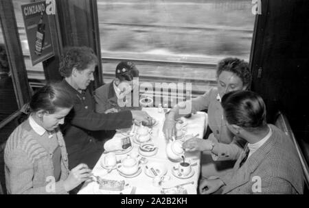 Photo de la ligne de train sur le Leipzig-Gutenfuerst Hof-Munich-route. Ce train était connu pour ses 'allemande' tout-voiture-restaurant, qui a été populaire en raison de la 1 : 1 taux de change, en particulier parmi les voyageurs de l'Allemagne de l'Est. Photo de train de boire du café et manger des gâteaux dans la voiture-restaurant. L'Allemagne de l'employé de chemin de fer (à gauche) avec ses deux enfants assis à la table avec une femme de Munich et un étudiant du village. Banque D'Images