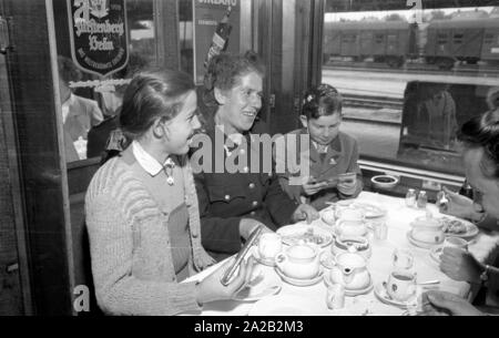 Photo de la ligne de train sur le Leipzig-Gutenfuerst Hof-Munich-route. Ce train était connu pour ses 'allemande' tout-voiture-restaurant, qui a été populaire en raison de la 1 : 1 taux de change, en particulier parmi les voyageurs de l'Allemagne de l'Est. Photo de train de boire du café et manger des gâteaux dans la voiture-restaurant. L'Allemagne de l'employé de chemin de fer (à gauche) avec ses deux enfants assis à la table avec une femme de Munich et un étudiant du village. Banque D'Images