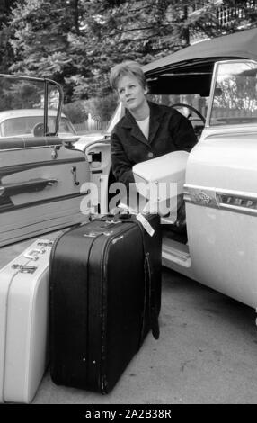 L'actrice et chanteuse Heidi Bruehl déchargement d'une voiture. Elle s'assoit sur le côté sur le siège conducteur et prend ses bagages hors de la voiture. Banque D'Images