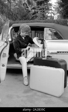 L'actrice et chanteuse Heidi Bruehl déchargement d'une voiture. Elle s'assoit sur le côté sur le siège conducteur et prend ses bagages hors de la voiture. Banque D'Images