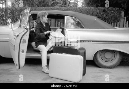 L'actrice et chanteuse Heidi Bruehl déchargement d'une voiture. Elle s'assoit sur le côté sur le siège conducteur et prend ses bagages hors de la voiture. Banque D'Images