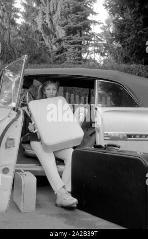 L'actrice et chanteuse Heidi Bruehl déchargement d'une voiture. Elle s'assoit sur le côté sur le siège conducteur et prend ses bagages hors de la voiture. Banque D'Images