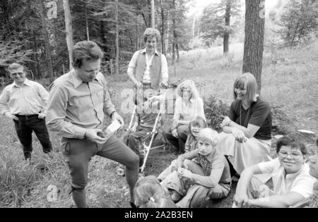 Une journée de la forêt a été organisée pour les enfants handicapés avec une excursion à la forêt bavaroise à proximité de Kelheim. La photo montre un forestier, qui donne à l'arbre pour enfants différents disques touchez et regardez. Banque D'Images