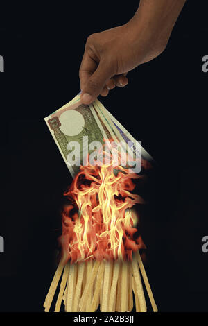 Man's hand holding devise indienne et de brûler dans le feu sur fond isolé. Banque D'Images