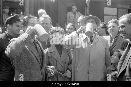 La photo montre probablement membres de l'expédition dans l'Himalaya à la large pic entre août et décembre 1954. Le voyage pour la région himalayenne explique le jour de départ le 28 avril. Les alpinistes participantes disent au revoir à leurs proches et les parties intéressées à la gare principale de Munich. Les participants ont vite boire une dernière bière bavaroise. Banque D'Images