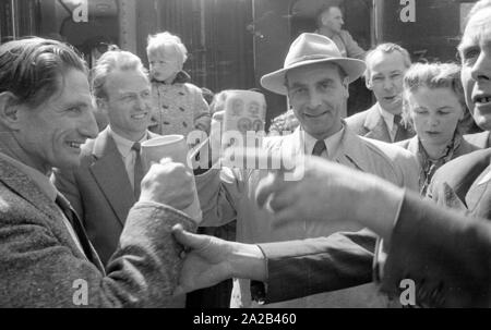 La photo montre probablement membres de l'expédition dans l'Himalaya à la large pic entre août et décembre 1954. Le voyage pour la région himalayenne explique le jour de départ le 28 avril. Les alpinistes participantes disent au revoir à leurs proches et les parties intéressées à la gare principale de Munich. Les participants ont vite boire une dernière bière bavaroise. Banque D'Images