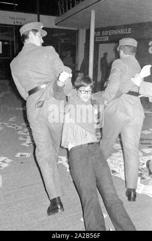 Les membres de l'Opposition Ausserparlamentarische Opposition extra-parlementaire (APO) a obtenu l'accès à une campagne électorale de la CSU avec de faux billets dans l'Bayernhalle à Munich. Photo de policiers de retirer un membre de l'APO du Bayernhalle. Banque D'Images