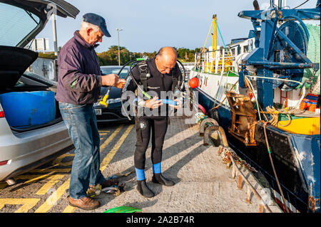 Schull, West Cork, Irlande. 2e oct, 2019. Le capitaine et le propriétaire du chalutier "Laetitia", Thomas Sheehan, aide un plongeur avec son équipement avant qu'il plonge pour effacer l'hélice du bateau de corde et d'un crabe potn. Le chalutier se prépare à faire un voyage de pêche de dernière minute avant de Storm Lorenzo hits Irlande demain. Met Eireann a émis un avertissement de vent Orange Statut Statut et un avertissement de pluie jaune pour la côte ouest de l'Irlande à partir de jeudi de 9h00 jusqu'à le même temps vendredi. Credit : Andy Gibson/Alamy Live News. Banque D'Images