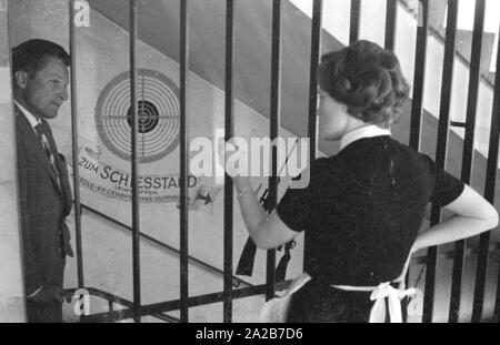 Un homme portant un costume parle à une femme pendant qu'il marche dans les escaliers à la plage de prise de vue. L 'Pistolen-Club-Bavaria e.V.' a été fondée le 7 novembre 1961, et dans les premières années exploité un champ de tir dans le sous-sol de l'Mathaeser complexes, non loin de la Stachus à Munich. Photo non datée, probablement dans les années 1960. Banque D'Images